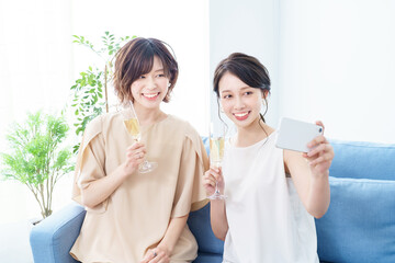 シャンパングラスを手に撮影する女性2人 
