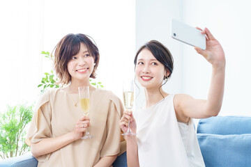 シャンパングラスを手に撮影する女性2人   © maru54