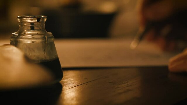 man writing using a dip pen and ink at his desk