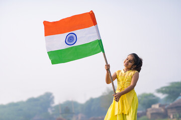 Cute indian little girl waving national tricolor flag at agriculture field.