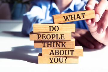 Close up on businessman holding a wooden block with "What Do People Think About You?" message