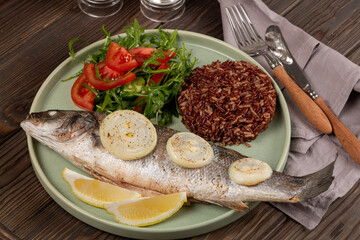 Fototapeta na wymiar Baked sea bass with brown rice and fresh salad