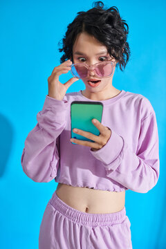 Teenage girl reading shocking news on smartphone