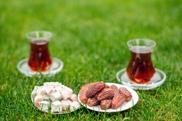 Dry Dates in a bowl and tea in armudu glass. Ramadan kareem.  Outdoor  background.