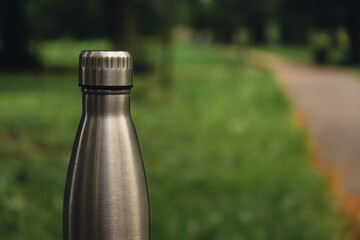 Water bottle. Reusable steel thermo water bottle on green grass. Sustainable lifestyle. Plastic...