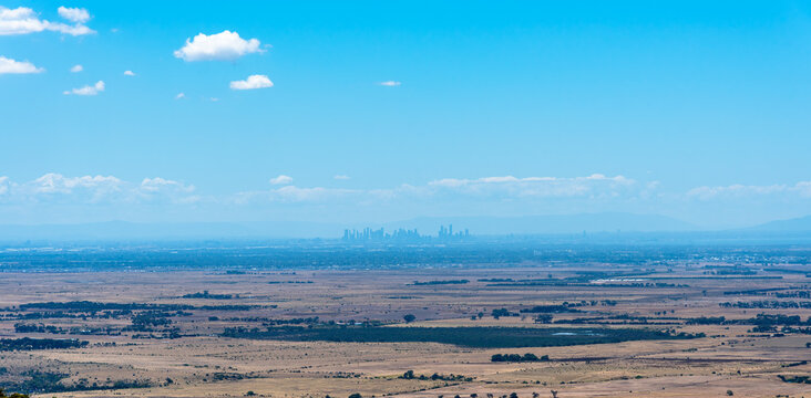 The city buildings of Melbourne, Australia in the distance, as seen from the top of the You Yangs Ranges with agricultural fields in the foreground
