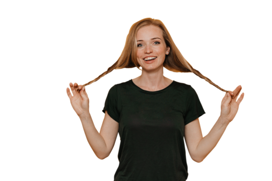 Beautiful redhead Irish girl in t-shirt twirls hair makes braids toothy smiles. Cheerful European carefree young woman holds tails satisfied by healthy hair. Student against transparent background.