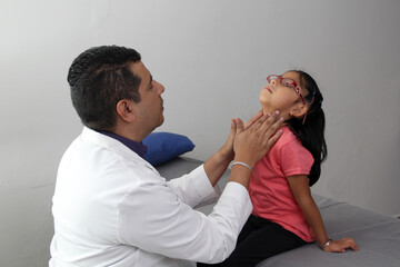 Professional specialist pediatrician doctor and patient 4-year-old Latino brown-haired girl are in consultation to check their eyes, mouth and throat to diagnose any disease in the office
