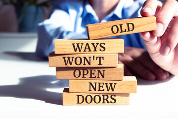 Close up on businessman holding a wooden block with "Old Ways Won't Open New Doors" message