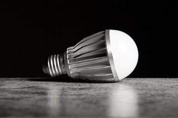 LED energy-saving lamp with aluminum radiator and E27 screw cap base on black background, copy space.