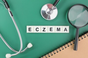 stethoscope, notebook, magnifying glass and alphabet word Eczema. a skin condition in which areas of the skin become red, rough, and sore. skin disease concept