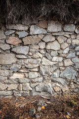 Old stone wall background with dry grass, vertical background.
