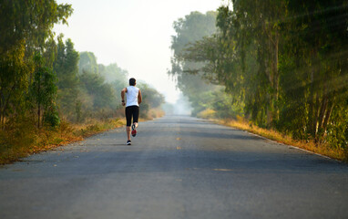 A man jogging alone through the road in morning.