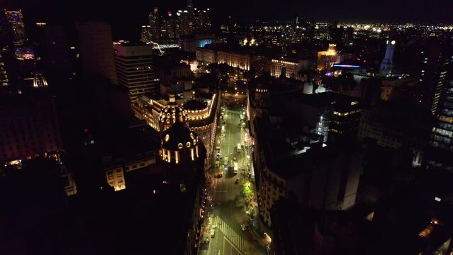 Dolly in aerial view of the chaotic city of Buenos Aires at night with the representative architecture of the rooftops of the ICBC bank headquarters and the Bencich building.