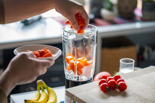 Woman hands making a healthy smoothie in the kitchen.Smoothie with bananas, carrots and tomatoes.Healthy eating concept image. 
