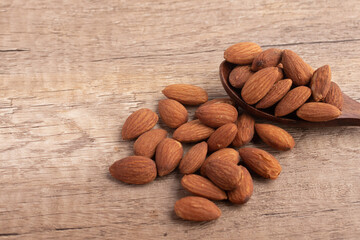 Salted almonds in wooden spoon on wooden background