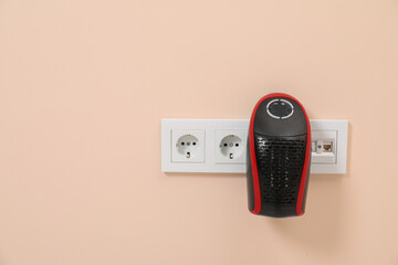 Modern compact electric heater charging from socket indoors, space for text