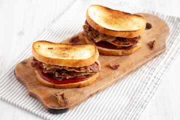 Homemade British Bacon Sandwich on a rustic wooden board, side view.
