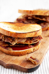 Homemade British Bacon Sandwich on a rustic wooden board, side view. Close-up.