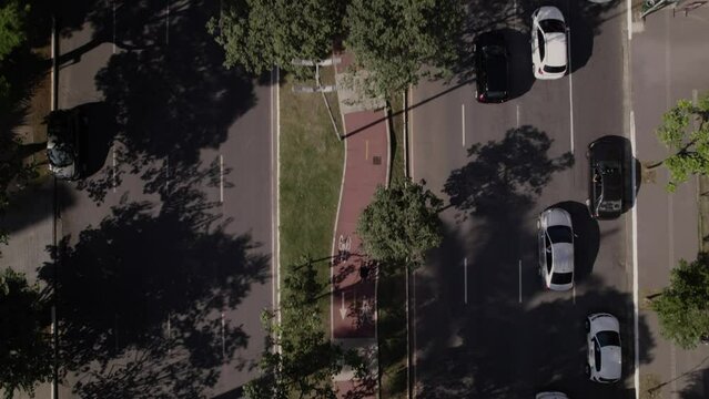 Drone top view showing a bike in a bike lane in the mide of a ood avenue with contrast betwen sunlight area and shady area.