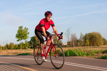 Naklejka premium Cycling Ideas. One Emotional Male Cyclist Riding Road Bike Uphill Equipped with Summer Bike Outfit Posing Outdoor During Training.