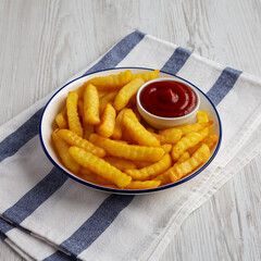 Homemade Unhealthy Crinkle French Fries with Ketchup on a Plate, side view.