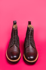 Pair of Premium Dark Brown Grain Brogue Derby Boots Made of Calf Leather with Rubber Sole Placed Over Pink Background.