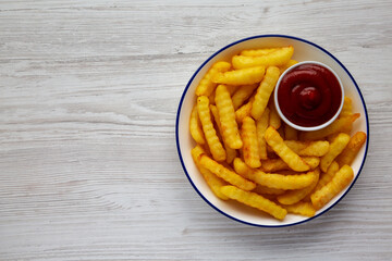 Homemade Unhealthy Crinkle French Fries with Ketchup on a Plate, top view. Flat lay, overhead, from above. Space for text.