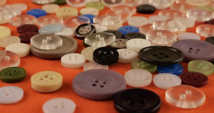 Plastic multi-colored buttons on an orange cotton fabric.