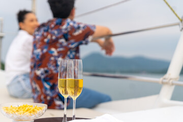 Asian couple relax and enjoy luxury outdoor lifestyle celebration party drinking champagne together while travel on luxury private catamaran boat yacht sailing in the ocean on summer holiday vacation.