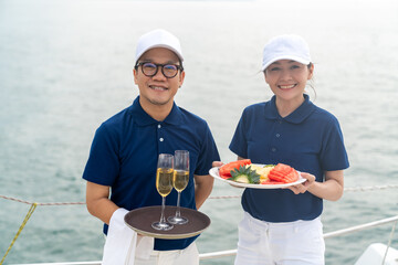 Portrait of Waiter and waitress holding fresh fruit and champagne for serving to passenger tourist...
