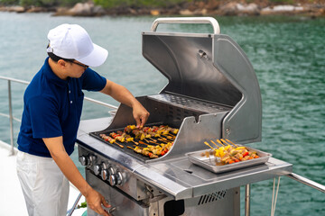 Asian man chef cooking grilled barbecue and seafood on stove for serving to passenger tourist...