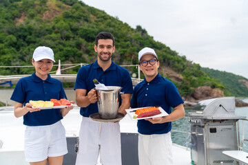 Portrait of Waiter and waitress holding food and drink for serving to passenger tourist travel on luxury private catamaran boat yacht on summer vacation. Cruise ship service occupation concept. - obrazy, fototapety, plakaty