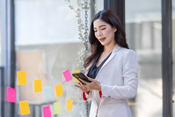 Portrait of Asian business woman using mobile phone application and pointing finger to smartphone...
