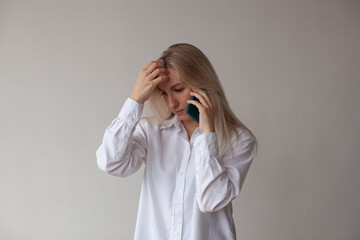 A young woman in a white shirt talking on the phone. White background.