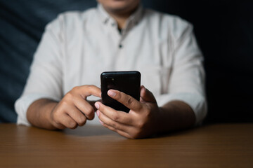 business man holding a smartphone and scrolling on a wooden table