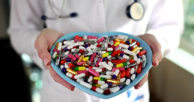 Doctor holding in hands plate in shape of heart with many medical capsules closeup 4k movie slow motion 