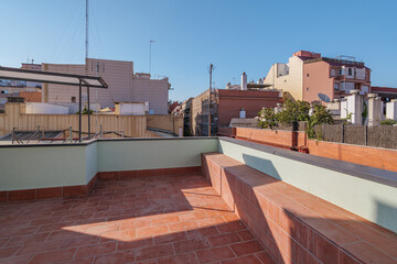 Big sunny terrace on the roof of modern building lined with red brick tiles overlooking the neighboring houses. Summer playground for leisure activities, party and meetings with friends.