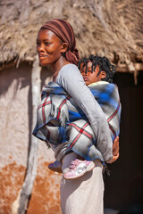 Fototapeta na wymiar village african mother carrying her child in the back