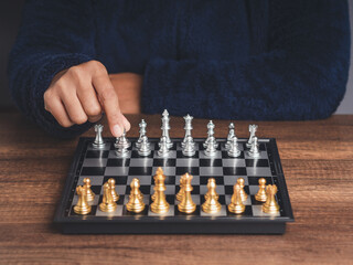 A businessman in a sweater playing chess while sitting at the table