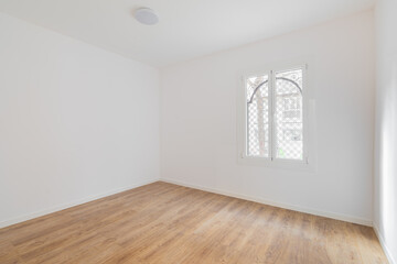 Empty room with laminate flooring, newly painted white walls and bright window. Repair and construction concept.