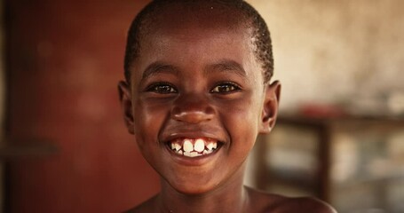 Close up portrait of a Cute Little African Kid with a Big Beautiful Smile Looking at the Camera. Happy Male Child in a Rural Area Representing Innocence, Peace and Hope. Documentary Footage