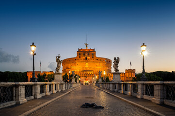 View of the illuminated Mausoleum of Hadrian, known as Castel Sant'Angelo from the Sant'Angelo bridge in blue hour before sunrise. - 562044911