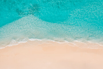 Summer seascape beautiful waves, blue sea water in sunny day. Top view from drone. Sea aerial view, amazing tropical nature background. Beautiful bright sea with waves splashing and beach sand concept