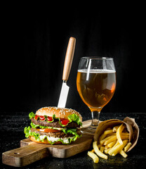 Burger with a knife,fries, beer in a glass.