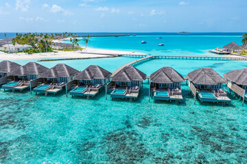 Tranquil aerial landscape, luxury tropical resort over water villas. Beautiful island beach, palm trees, sunny sky. Amazing bird eyes view in Maldives, paradise coast. Exotic tourism, relax nature sea