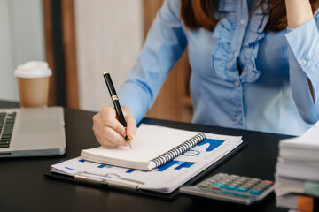 Businesswoman hand working with new modern computer and writing on the notepad strategy diagram as concept morning light.