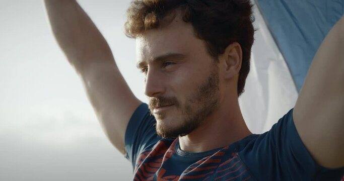 Close up of a young man with raised arms to hold a slovenian fag to flutter in the wind.