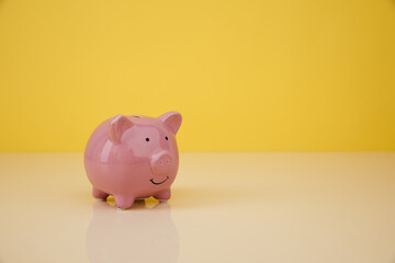 Investmenst and saving money concept. Piggy bank on yellow background with copy space