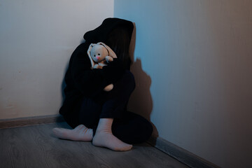 Teenager female girl crying in a corner with a toy, concept of bullying or abuse